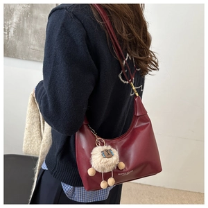 Detail of burgundy leather dumpling bag with a cute beige plush lamb charm