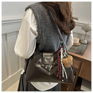 Gros plan d'un sac cabas rétro en cuir marron avec anneaux métalliques et pendentif ours