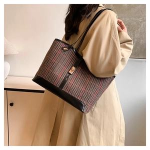 Détail du sac cabas pied-de-poule avec bordure en cuir noir et fermoir doré sur modèle
