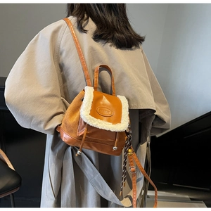 Détail d'un petit sac à dos en daim marron avec bordure en fausse fourrure blanche
