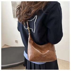 Detail of vintage dark brown faux leather hobo shoulder bag with golden hardware