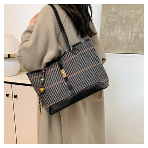 Détail du sac seau à carreaux avec fermoir doré et bordure en cuir sur manteau camel