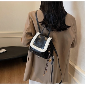 Détail d'un mini sac à dos noir et blanc avec bordure en laine et relief sur le cuir