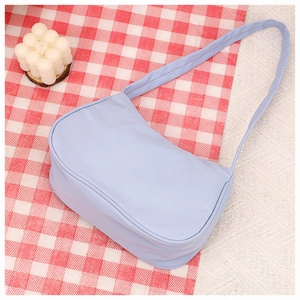 Flat lay of a light blue minimalist crescent underarm bag on a red checkered tablecloth