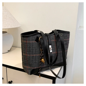 Détail du sac cabas à carreaux contrastés avec fermoir rotatif et breloque cloche dorée