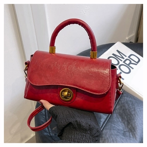 Détail du sac bandoulière en cuir ciré rouge avec fermoir doré et poignée