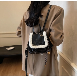Détail du mini sac à dos noir avec bordure en polaire blanche et breloque clochette