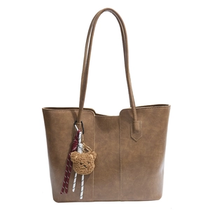 Classic brown leather tote bag with a cute bear charm and woven tassel detail