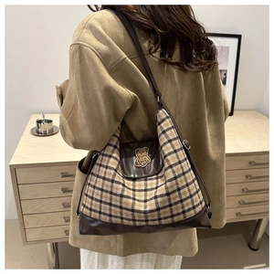 Detail view of vintage plaid tote bag with bear patch on a model in a warm setting
