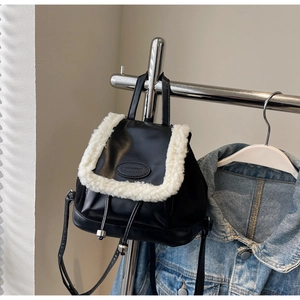 Détail d'un mini sac à dos rétro en cuir noir avec bordure en fausse fourrure blanche