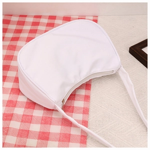 Detailed top view of a white minimalist half-moon crescent underarm bag on fabric