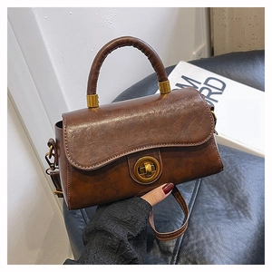 Détail du sac à main en cuir marron foncé avec fermoir rotatif circulaire en laiton vieilli