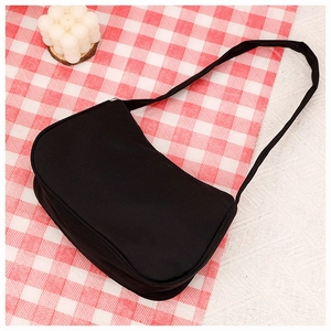 Detail of minimalist black canvas crescent bag placed on a red and white checkered cloth