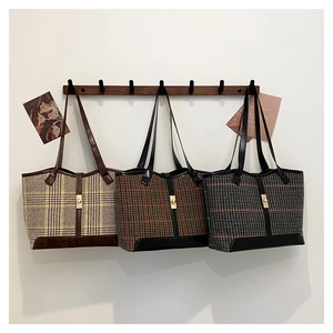 Vue de trois sacs cabas vintage à carreaux en beige, marron et gris suspendus au mur