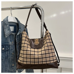 Detail of checkered tote bag with plush bear patch and premium brown leather straps