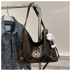 Detailed view of dark brown leather Hobo bag with golden M logo and white plush charm