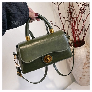 Détail du sac à main vert olive en cuir avec fermoir rotatif doré et finition brillante