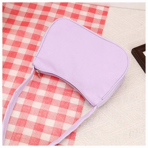 Close-up of light purple crescent shoulder bag with zipper on red checkered cloth