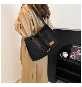 Model view of black corduroy tote bag with fashion label and large capacity design