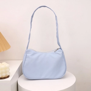 Minimalist light blue crescent underarm bag displayed on a sleek white pedestal