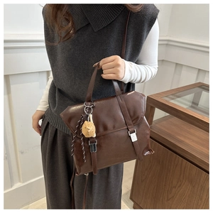 Détail d'un sac cabas marron foncé vintage en cuir huilé avec un charmant pendentif chat