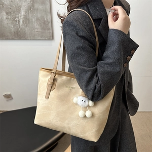 Modische beige Tragetasche mit Goldschrift und Plüsch-Anhänger für stilvolle Pendler