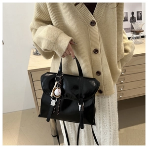 Détail d'un sac cabas noir vintage avec boucles argentées et pendentif de baseball
