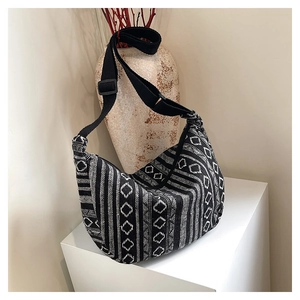 Detail of hobo bag featuring black and white geometric woven pattern and wide strap