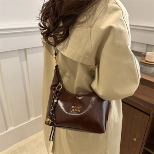 Sac à bandoulière croissant en cuir marron avec détails dorés et pendentif clochette