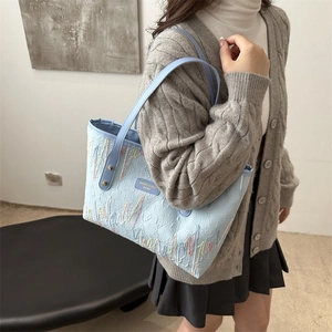 Light blue faux leather tote bag with 3D floral embossing and colorful embroidery detail