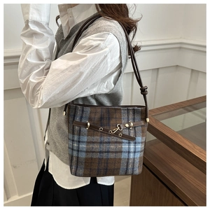 Detail of vintage plaid bucket bag featuring brown leather trim and metallic buckle