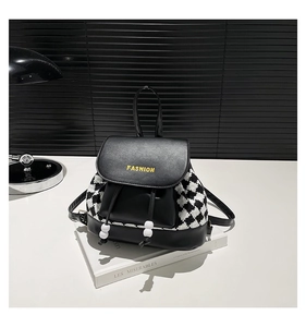 Detail view of mini checkered backpack with gold Fashion lettering on white book