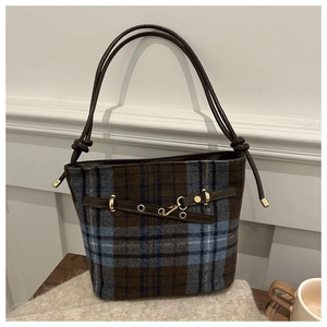 Close-up of blue and brown tweed bucket bag with leather strap and gold metal hardware