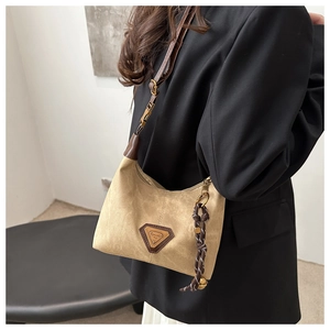 Détail du sac cabas kaki avec garniture en cuir marron et pendentif métallique