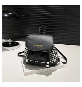Detail view of large capacity backpack featuring black leather and houndstooth pattern fabric
