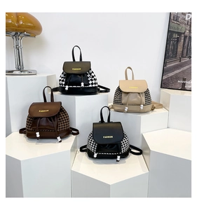 Close-up of four plaid tweed and leather mini backpacks on geometric display stands