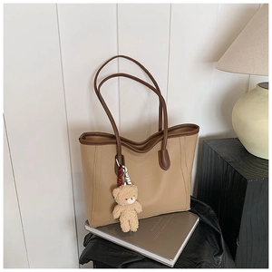 Détail du sac cabas en cuir kaki avec bordure marron et charmant pendentif d'ours en peluche