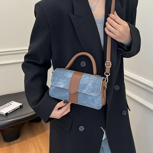 Retro contrast shoulder bag with blue denim texture and brown leather trim shown on model