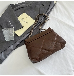 Dettaglio della borsa in pelle trapuntata marrone scuro con elegante catena in metallo e cuciture
