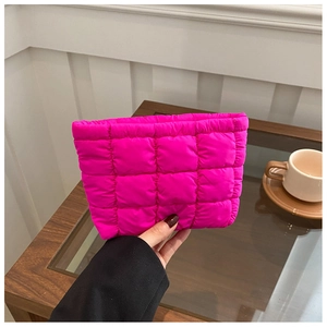 Detail of rose red quilted checkered cosmetic bag being held in a hand