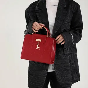 Red crocodile texture handbag with gold metal handle and deer charm accessory