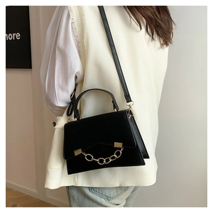 Détail du sac bandoulière en cuir noir avec chaîne dorée et poignée élégante