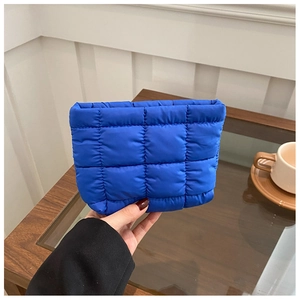 Close-up of royal blue quilted cosmetic bag with soft padded diamond texture design