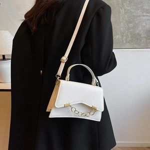 Sac à main blanc structuré avec chaîne dorée porté par un mannequin sur un blazer noir