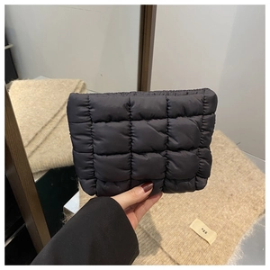 Detailed close-up of a quilted black puffy clutch bag made from waterproof nylon fabric