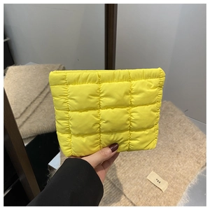 Detail shot of a vibrant yellow quilted puffy clutch with minimalist square stitching