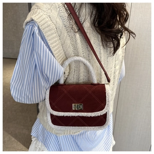 Detail view of burgundy quilted crossbody bag with white plush trim and gold metal lock