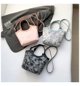 Détails de broderies sur sacs seau en soie disponibles en rose, bleu clair et noir