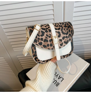 Detailed view of fashionable leopard print saddle bag with white patchwork and sleek strap.