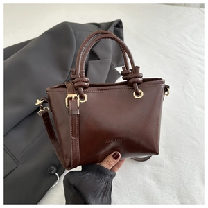 Detailed macro view of dark brown PU leather bucket bag with embossed fashion text and knots